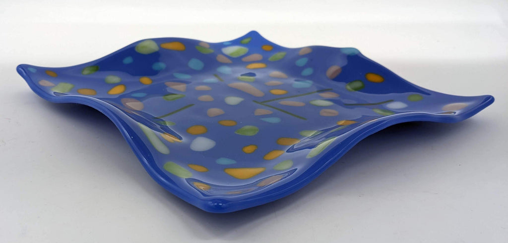 Blue glass square wavy plate with specks of purple, yellow, green, and light blue