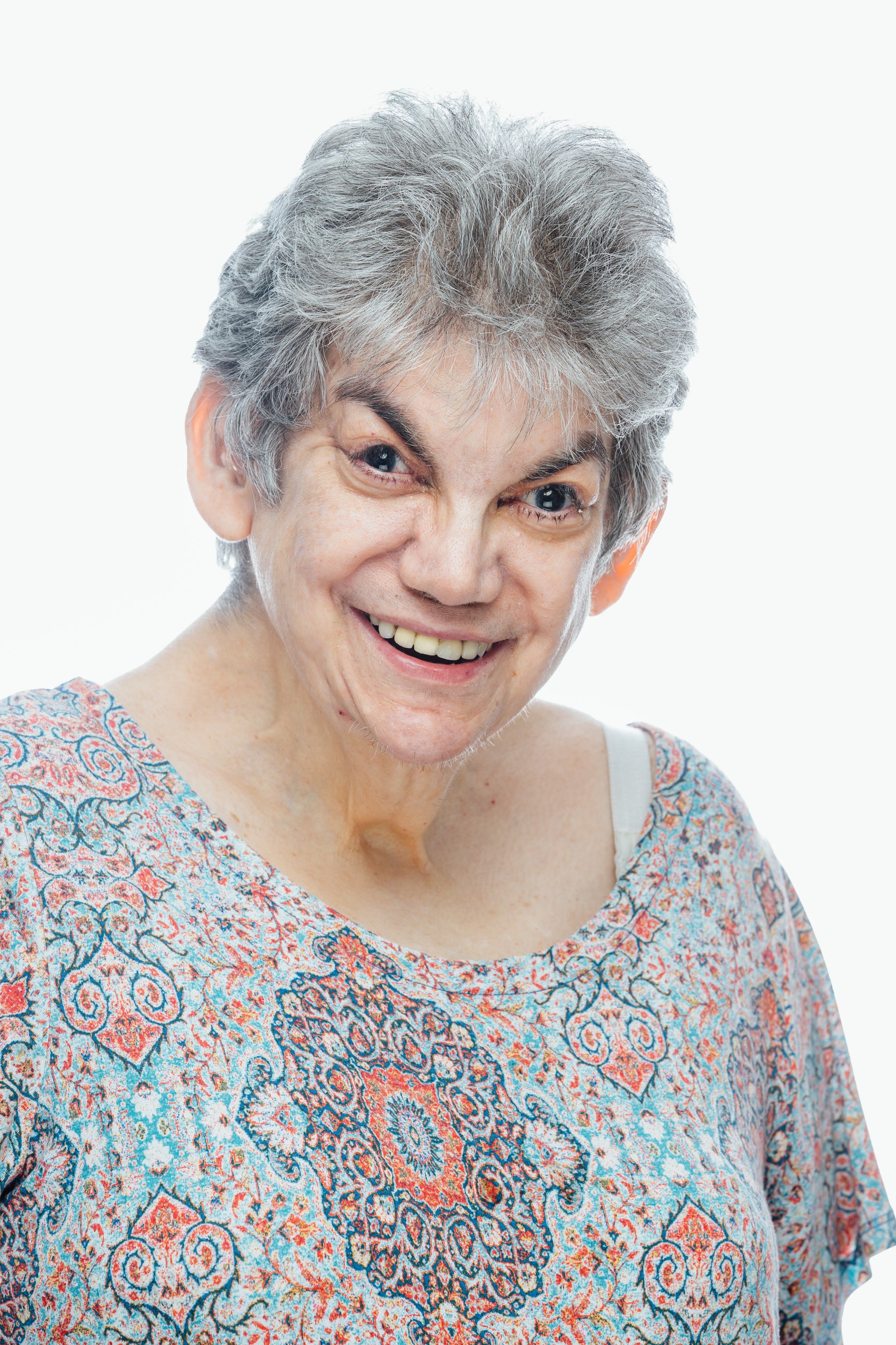Smiling woman with gray hair and multi colored blouse