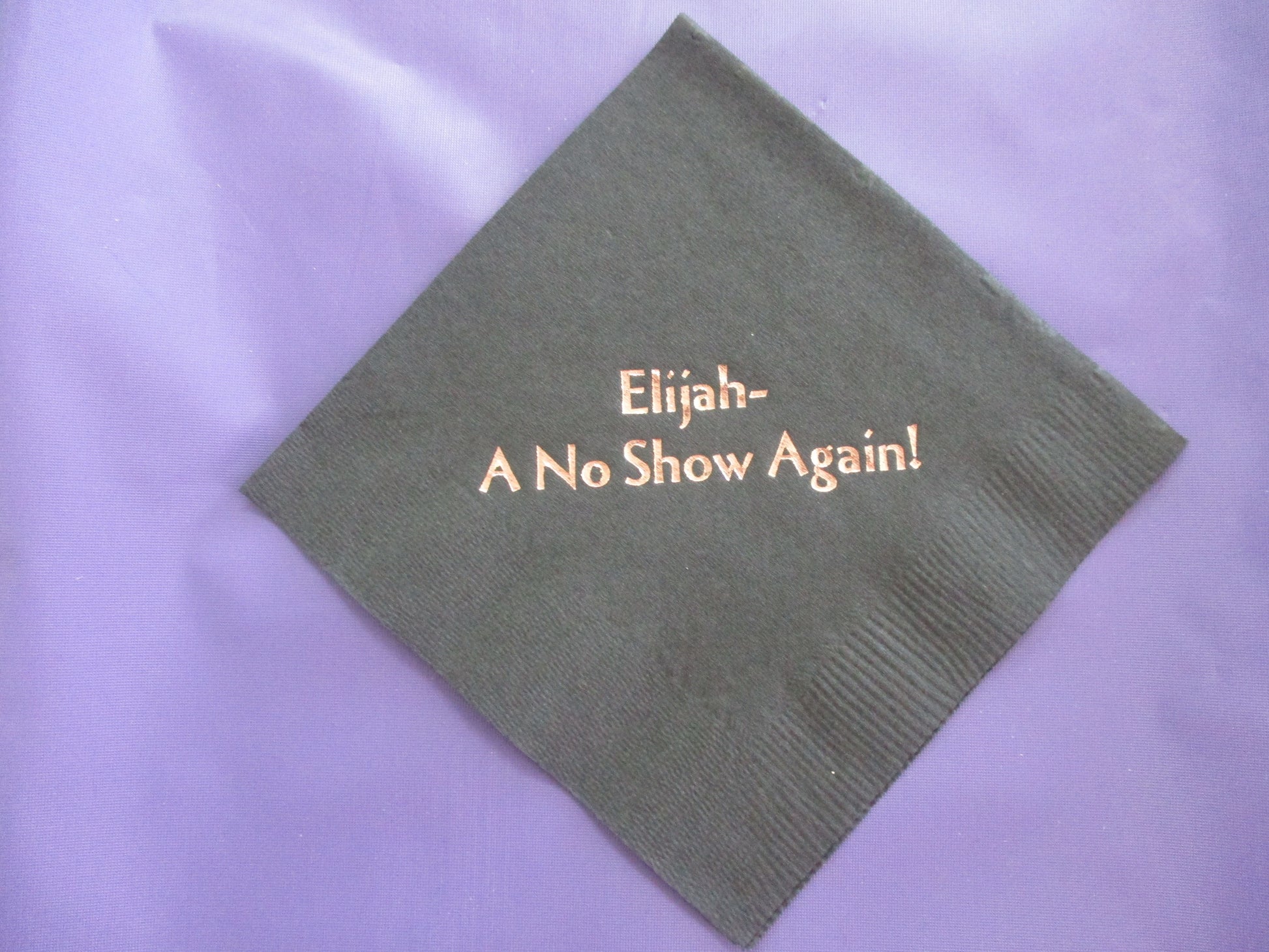 Black cocktail napkin with Elijah - A No Show Again! slogan