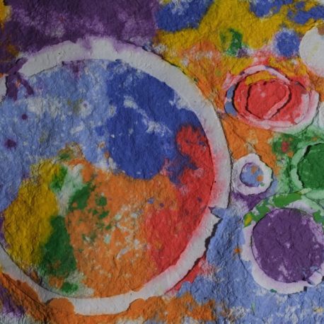 Pigment on recycled paper artwork with white circles against a background of purple, yellow, green, orange and blue colors