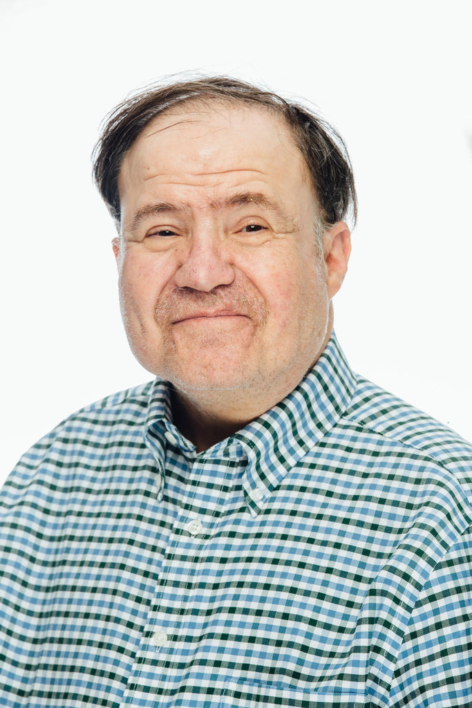 Smiling man with brown hair and green, blue and white checked polo shirt