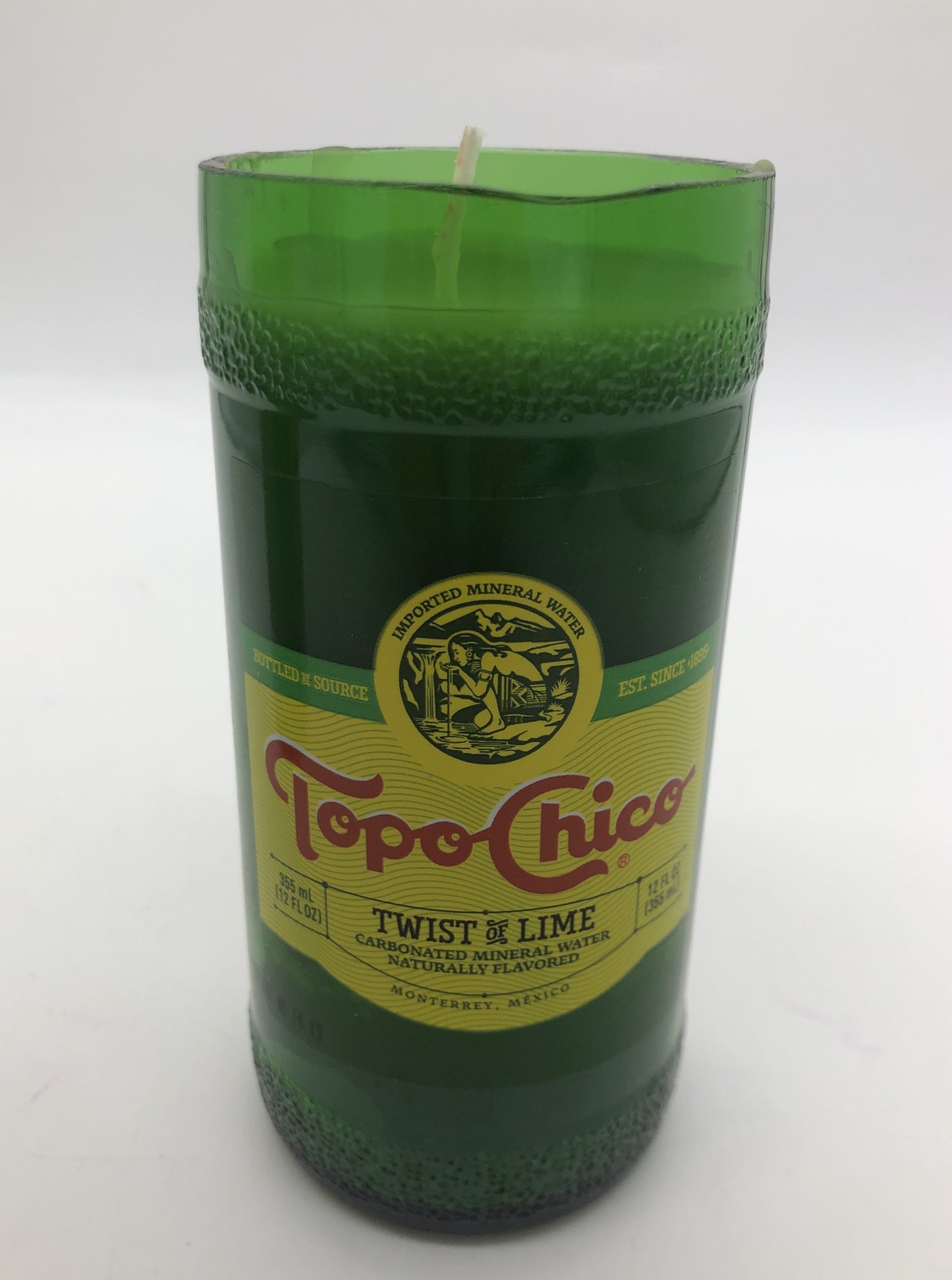 Cut green bottle of Topo Chico with light green candle inside.