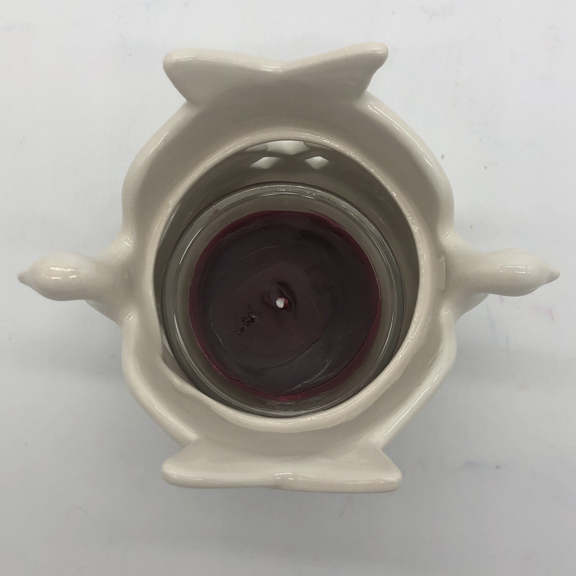 Top view of ceramic dove votive holder with maroon votive candle inside.