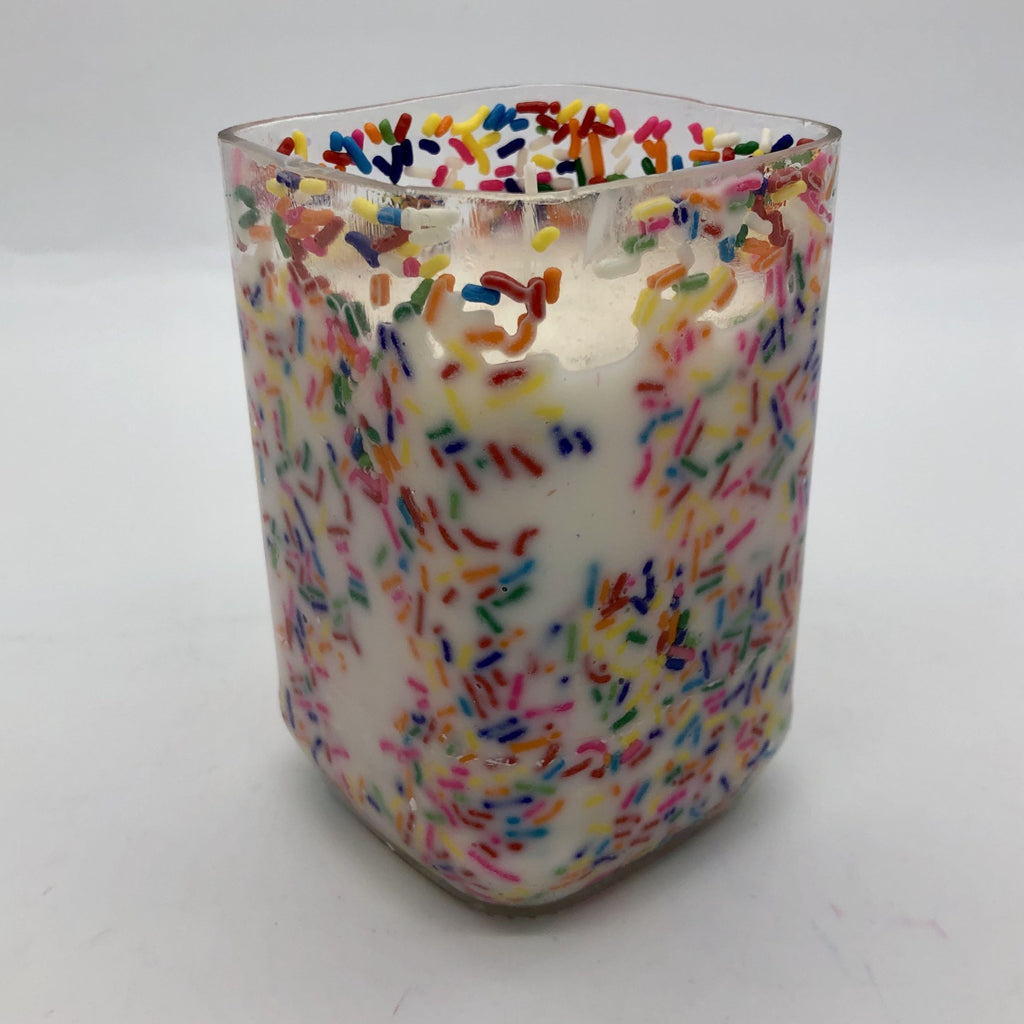 Square, clear wine bottle cut to 5 inches tall and filled with white wax and sprinkles