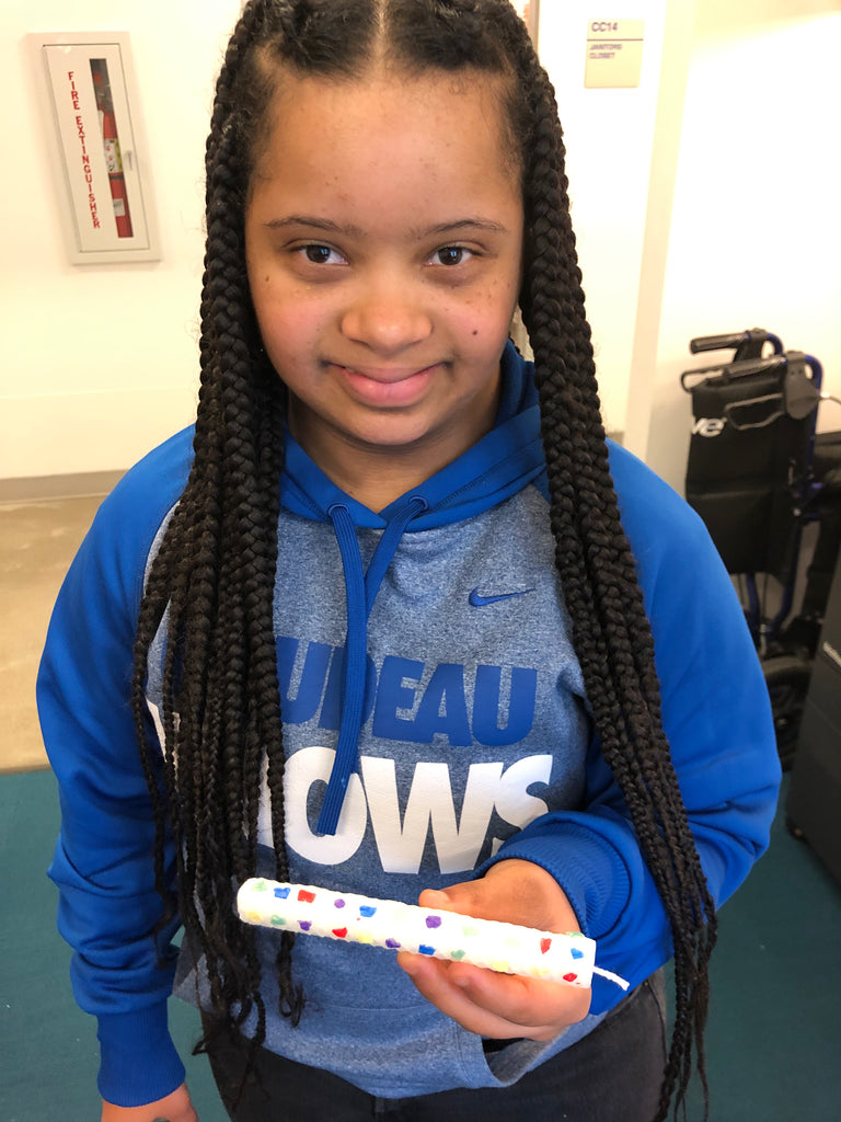 Young female holding up a confetti candle she made.