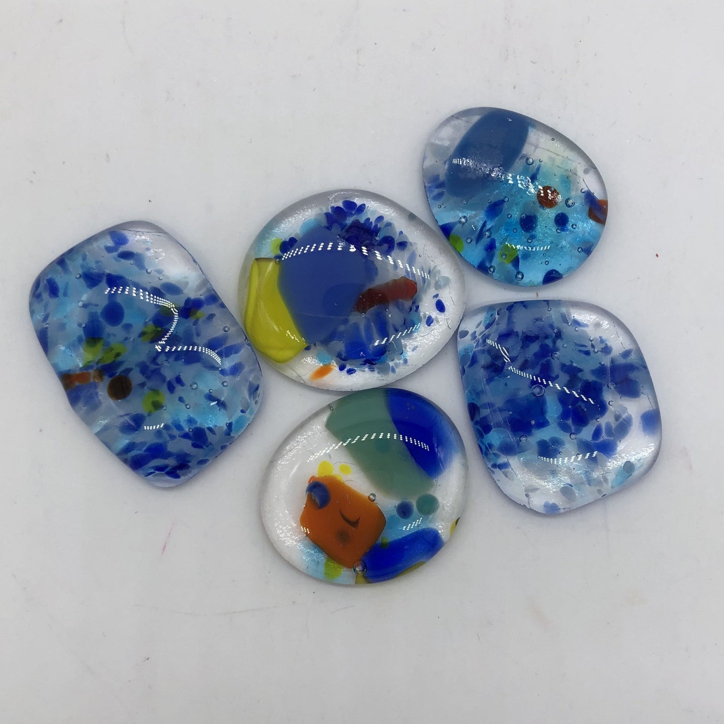 Five glass baubles of varying size and colors.  Mostly blue with accents of red, yellow and orange.