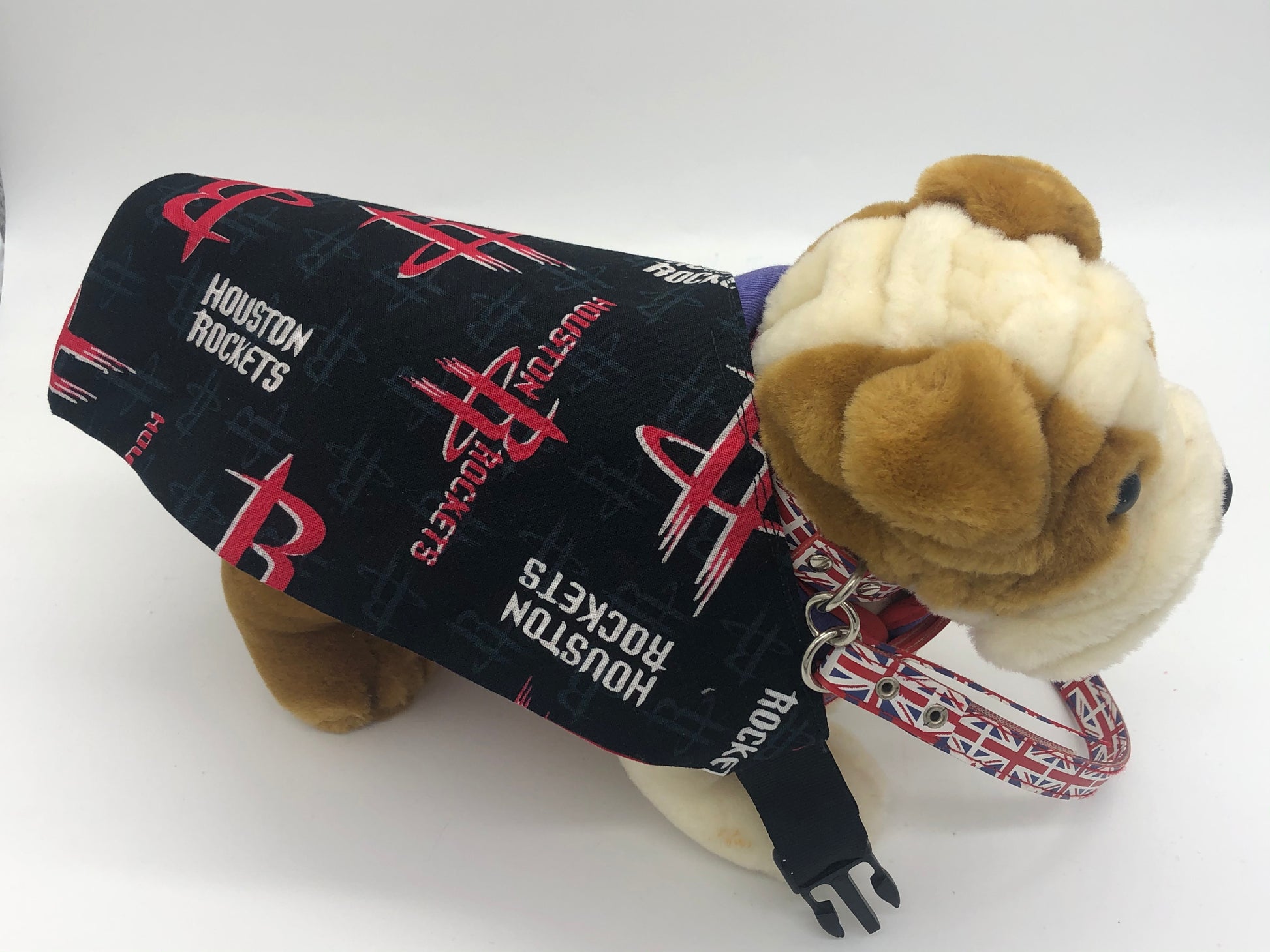Photo of a small stuffed brown and cream dog with a black and red triangular bandana with the Houston Rockets logo in red and white across it's back.