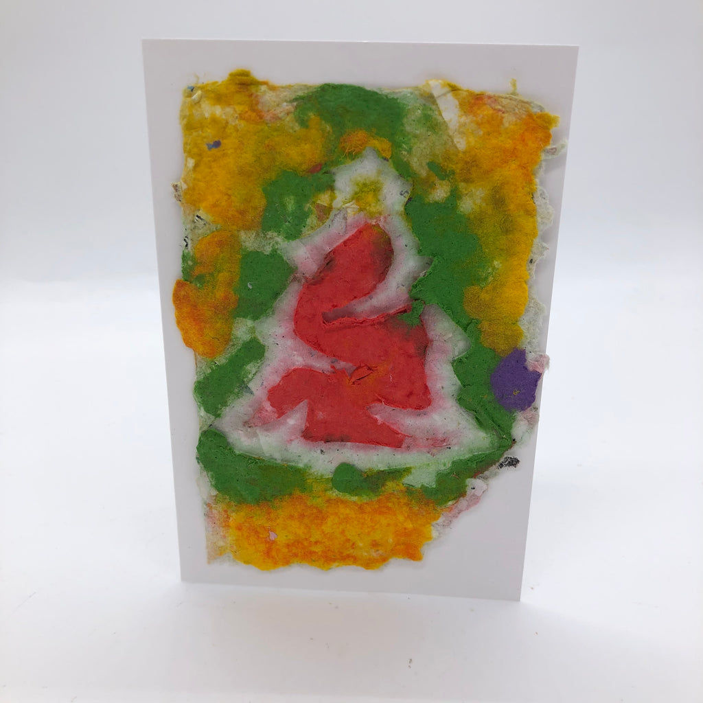Handmade paper greeting card with green and yellow background and red Christmas tree with white outline.