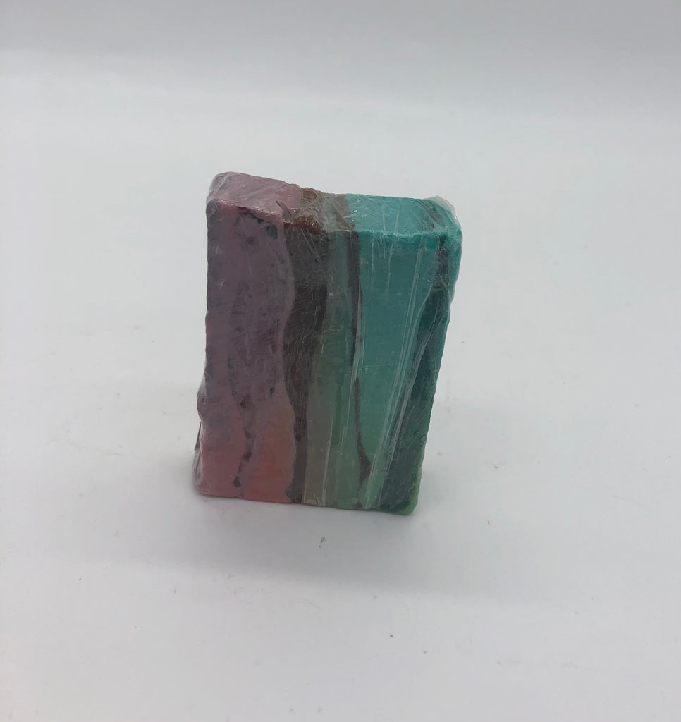 Rectangular bar of soap, standing on it's edge. Layers of colors including creamy plum, translucent purple, creamy aqua and translucent green.
