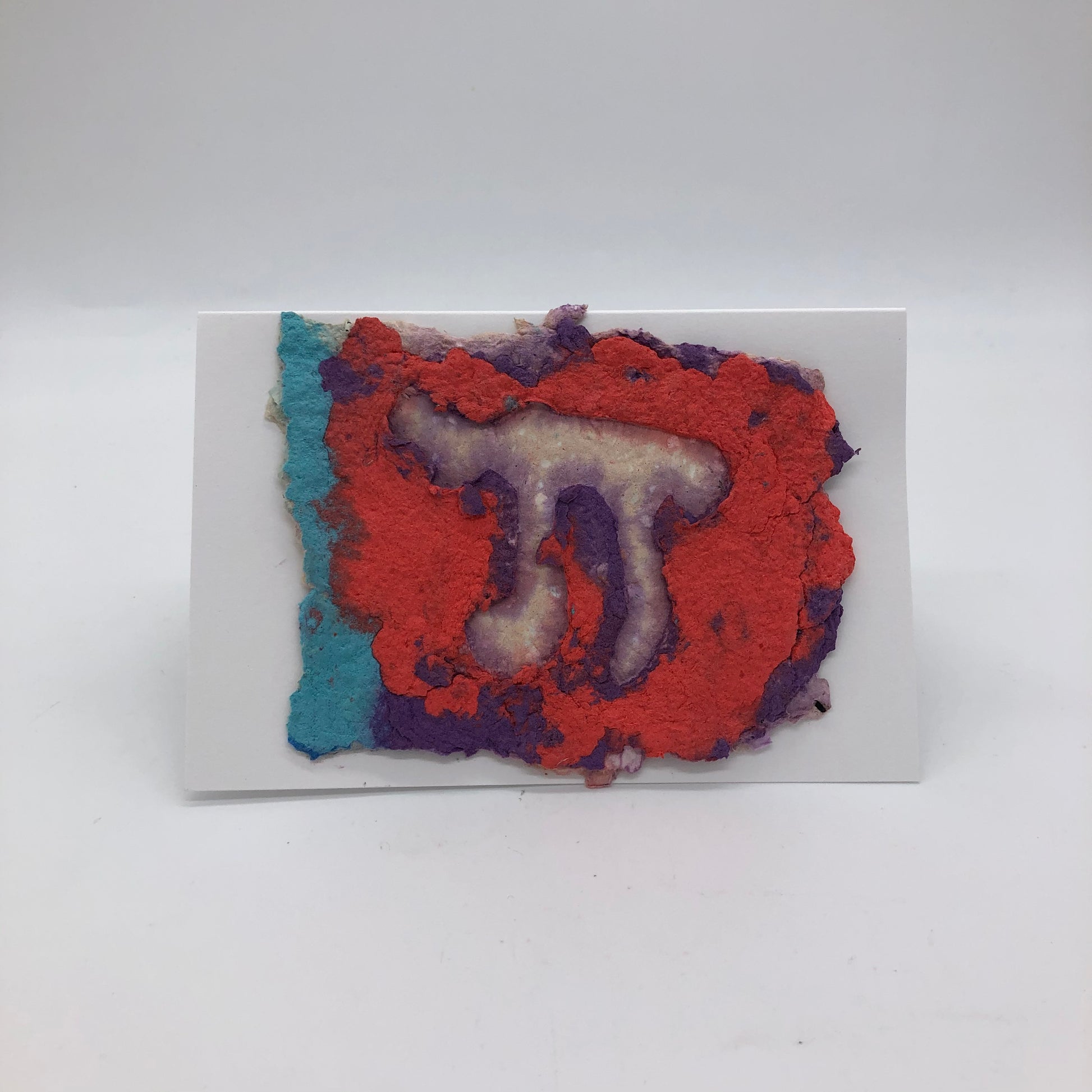Horizontal handmade paper greeting card with white Chai against purple, orange and a little tealbackground