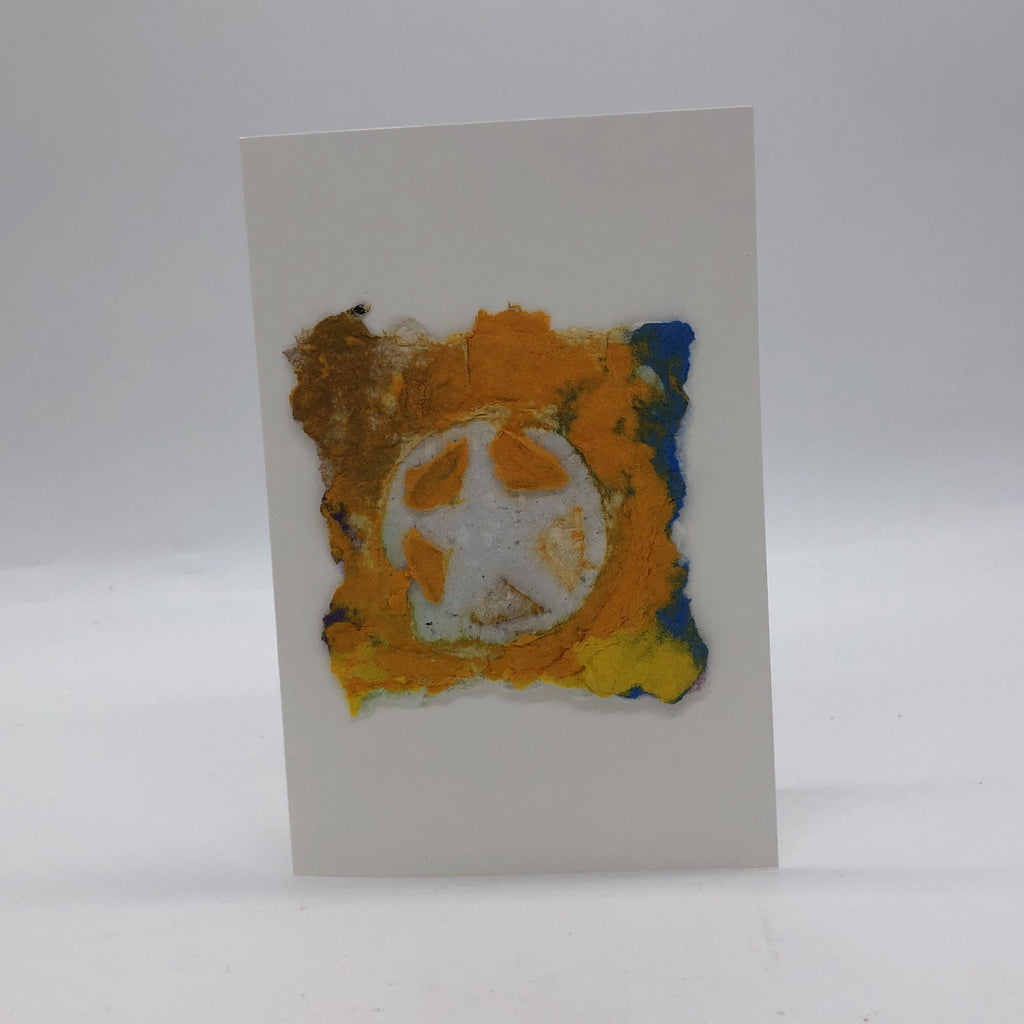 Handmade paper design on a white card. Art paper is yellow, golden and a little blue with a white star inside a white circle