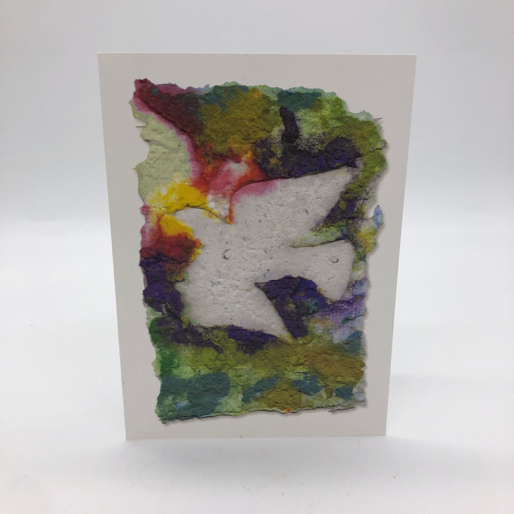 Greeting card printed with image of handmade paper in shades of purple, yellow, red and green.  On top of it is flying dove in white.