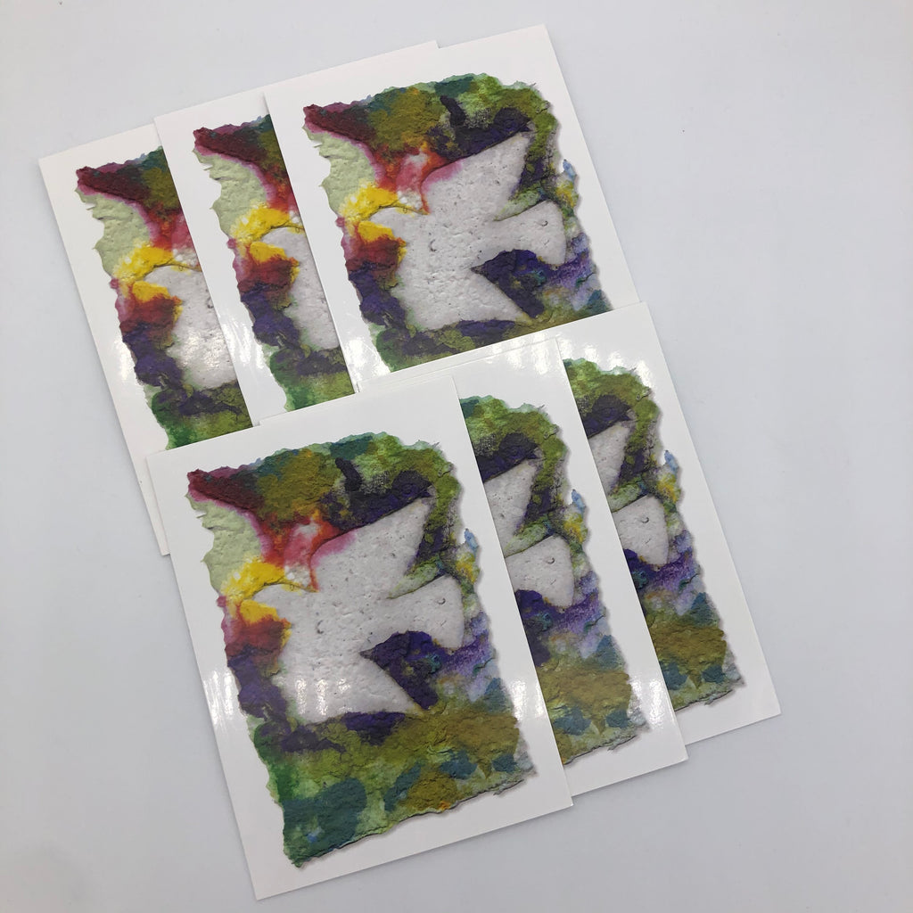 Photo of six of the greeting card.  Greeting card printed with image of handmade paper in shades of purple, yellow, red and green.  On top of it is flying dove in white.