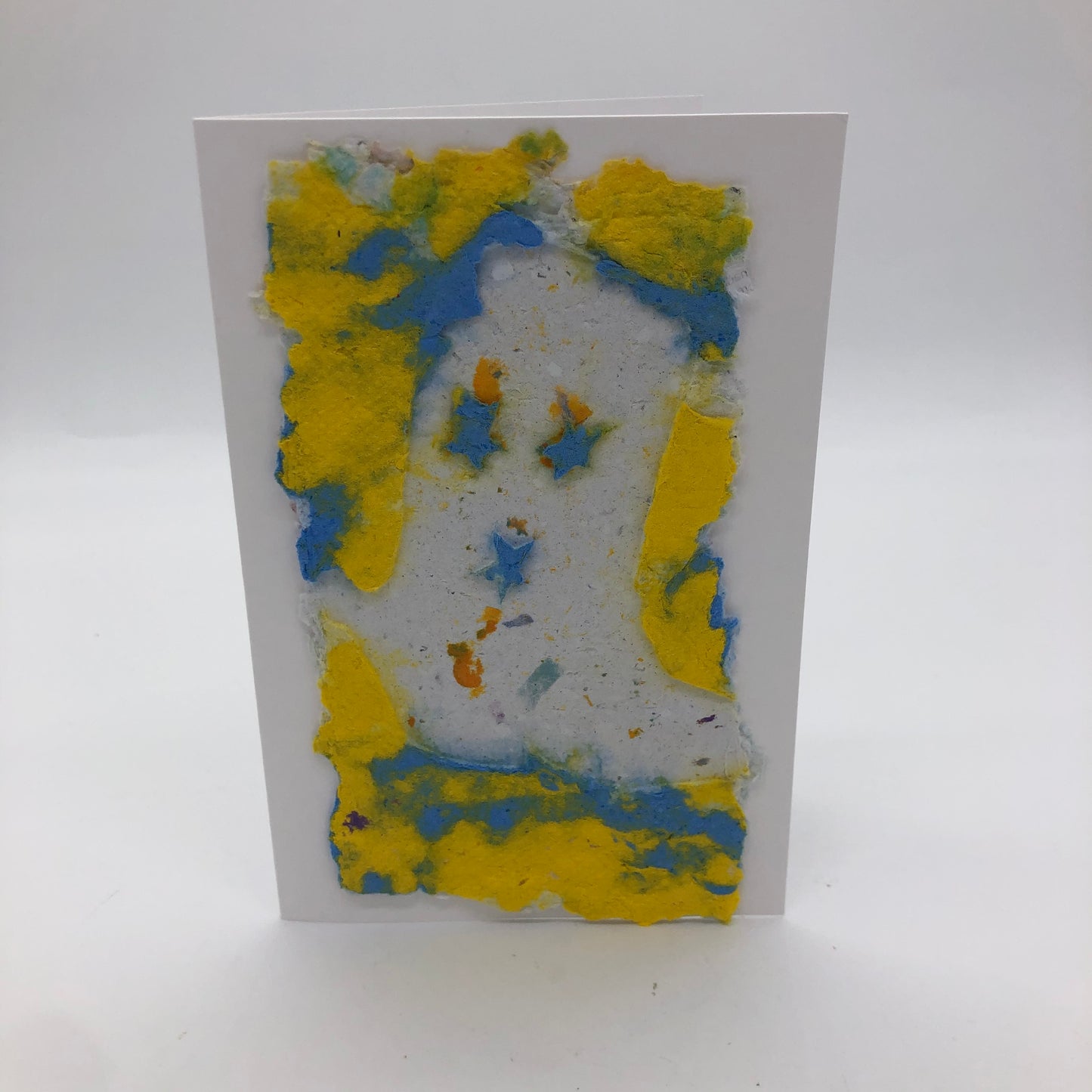 Handmade paper greeting card made in yellow and blue.  On top of card is a white cowboy boot with three blue stars.