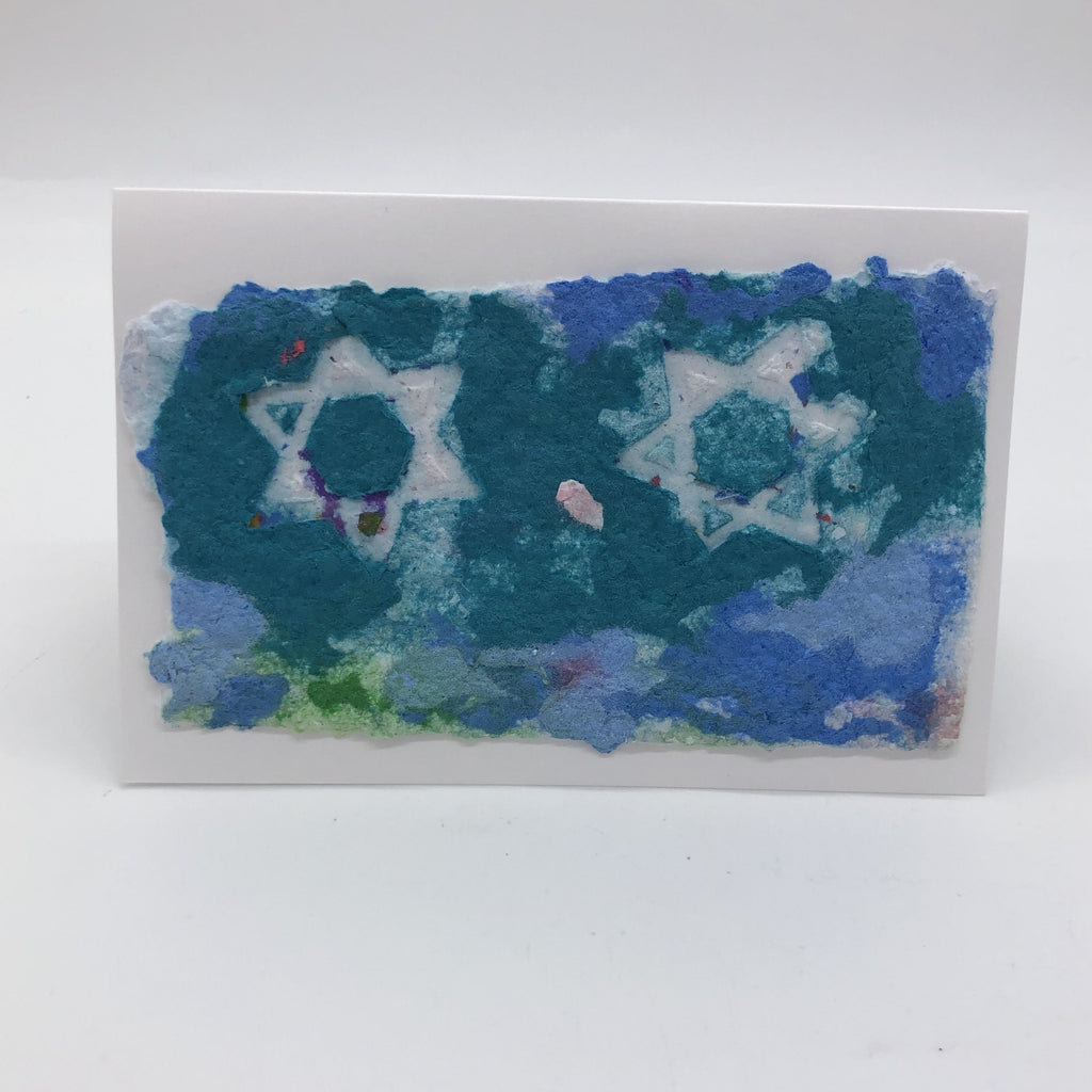 Handmade paper greeting card with background in shades of blue, green and teal.  There are two white outlined Star of David on top.