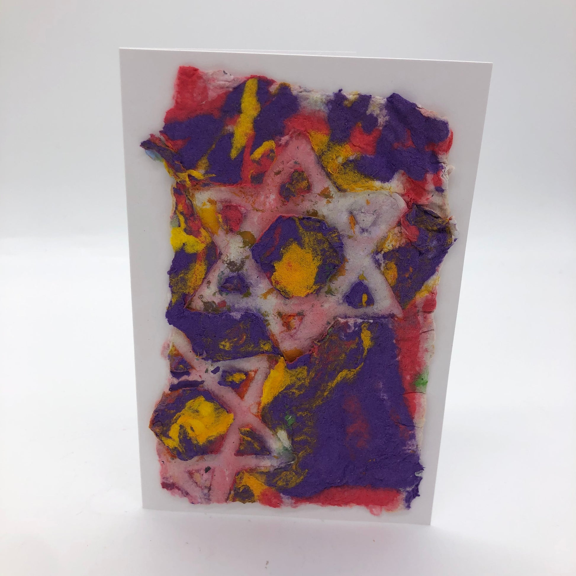 Two outlined Star of David in white.  Handmade paper of purple, pink and yellow.