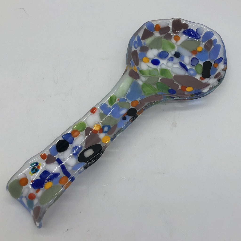 Clear glass spoonrest with long handle and wide bowl.  Decorated with many colors randomly placed.  Colors include medium blue, lavender, a little green, white, a few pieces of orange and yellow.