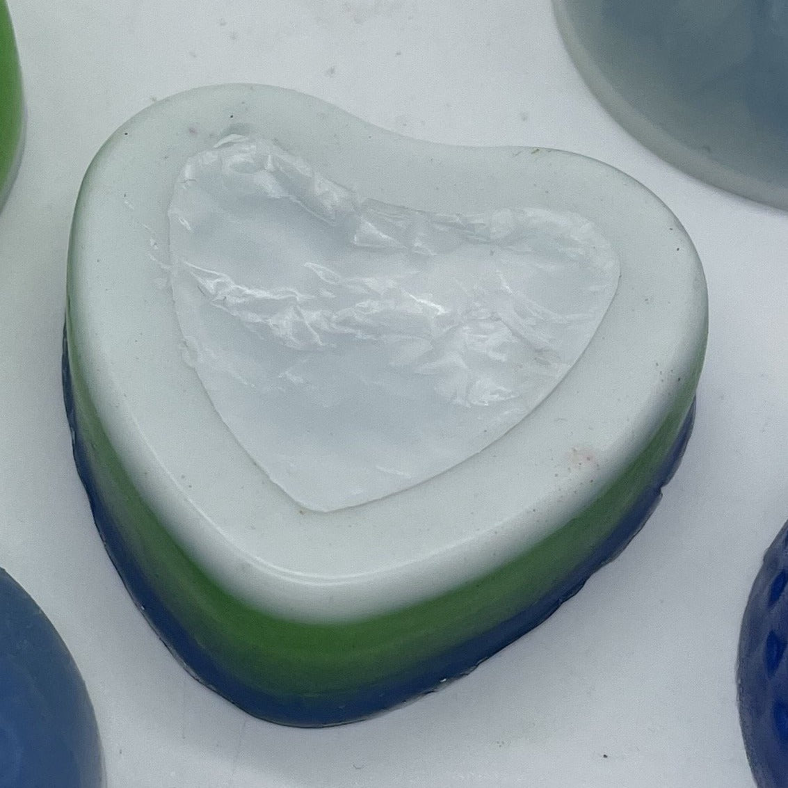 Heart shape soap layered in (from top) white, green and blue.