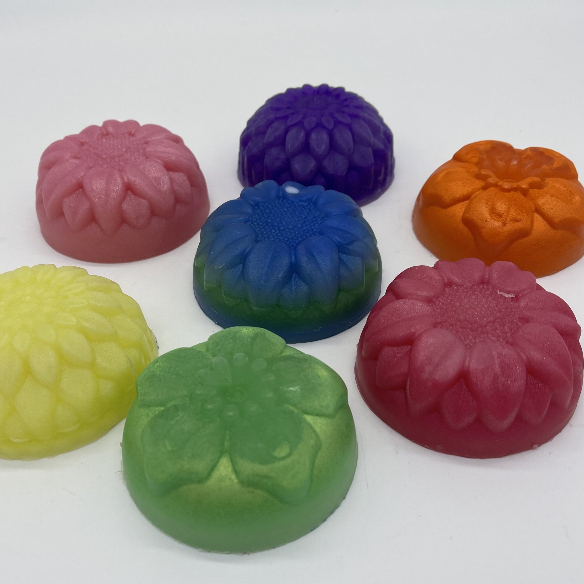 Several solid color round floral soaps including muted yellow, pink, purple, metallic light green, metallic orange and pinks.