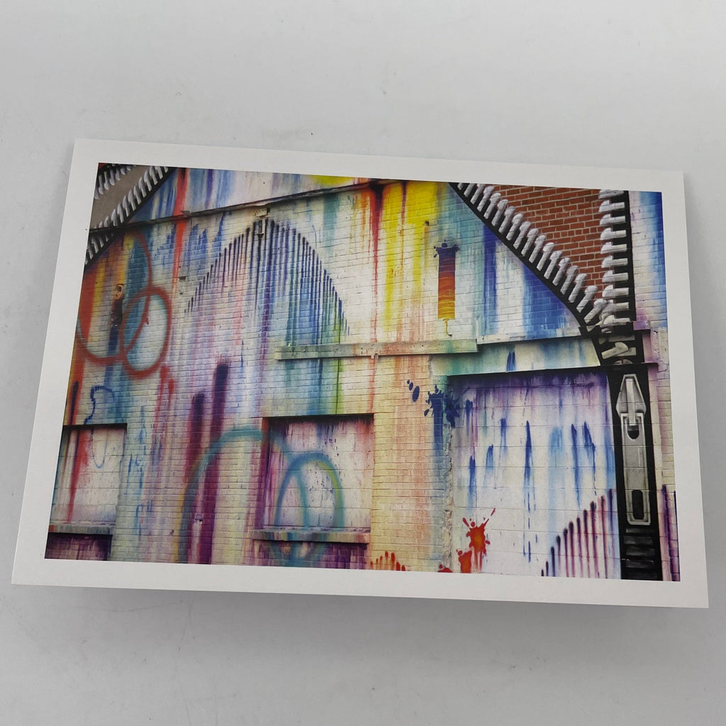 Greeting card with photo of brick building painted white with graffiti painted on it