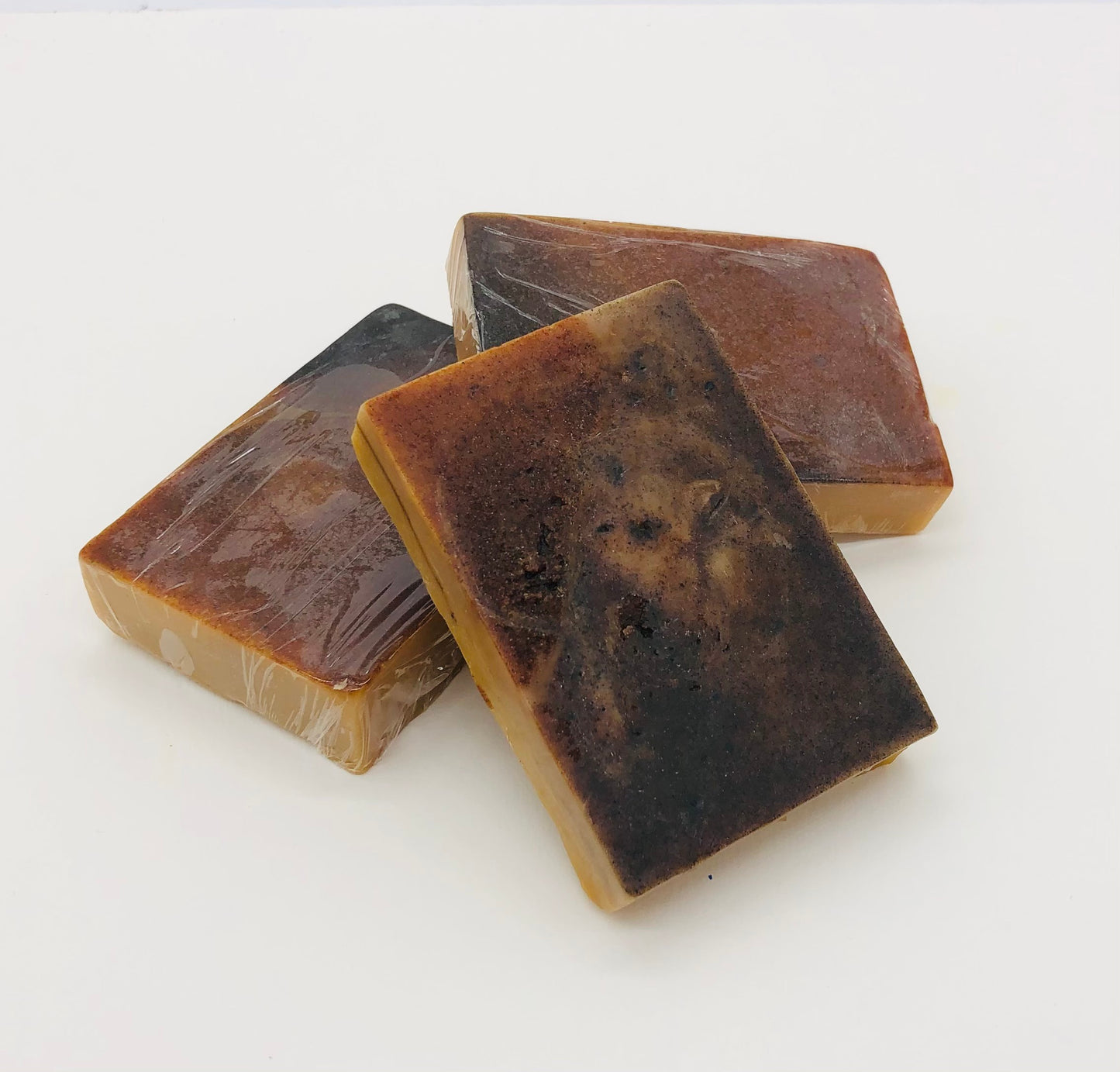 Three bars of soap with a caramel colored base and a mottled brown top layer .