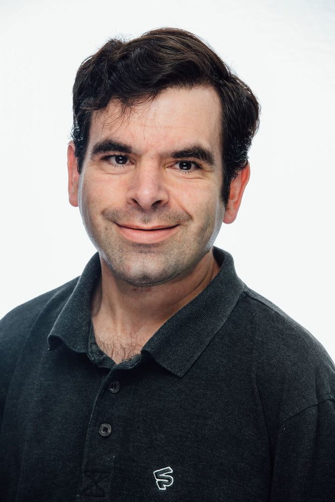 handsome young man wearing a black colored shirt and smiling at the camera