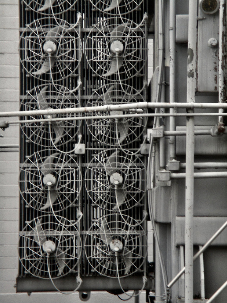 This is a black and white photo of 8 fans in an industrial setting