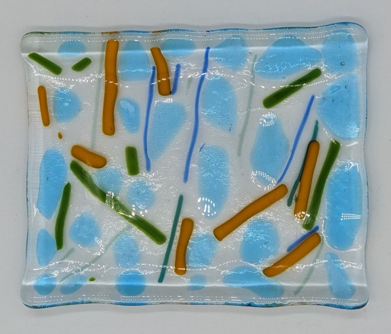 Clear glass soap dish/ small tray with chunks of light blue and lines of orange, green, and blue going in all directions