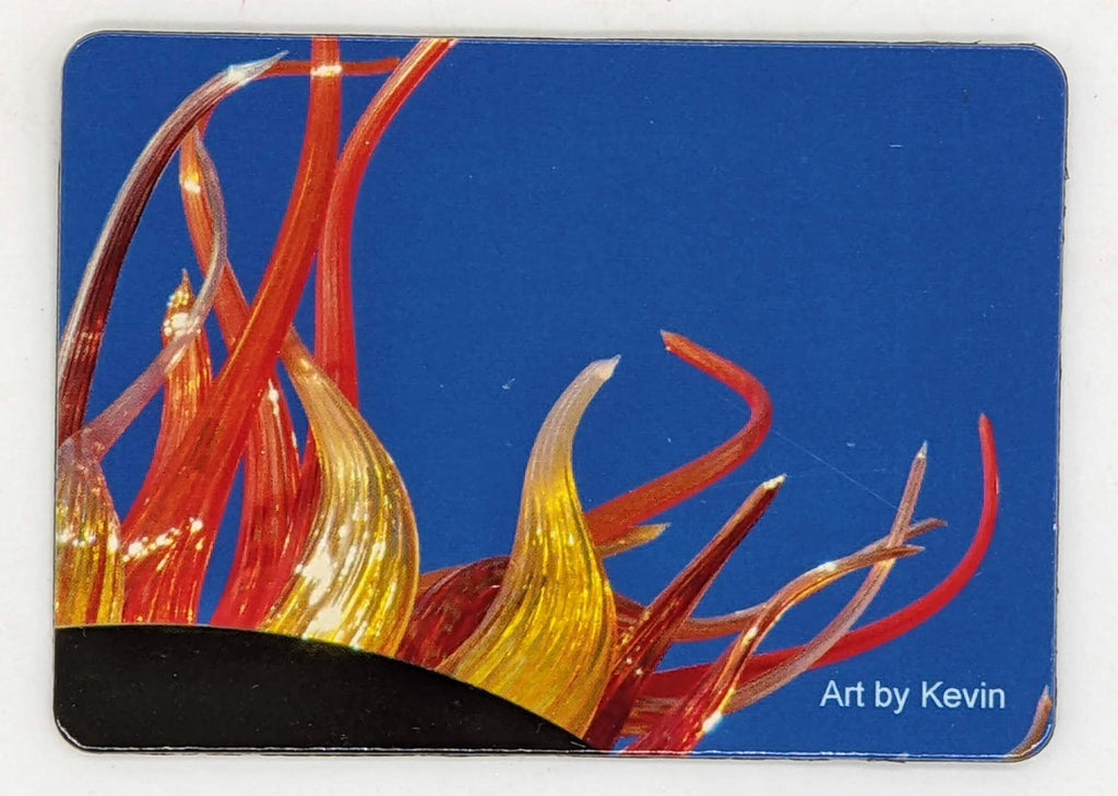 This is a magnet that says art by kevin, and has a photo of a blue background with red and yellow fiery glass coming out.