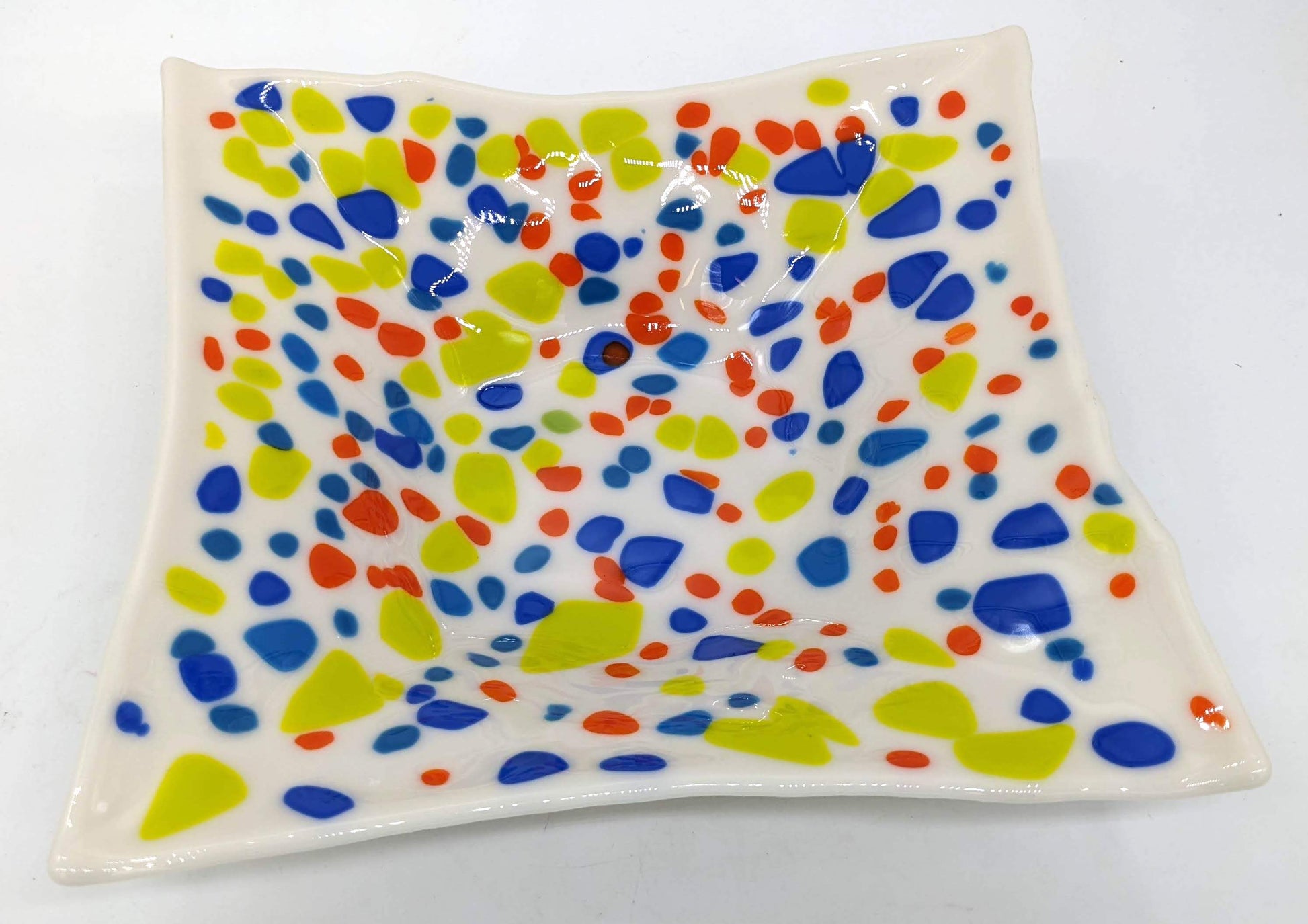 white square glass bowl with spots of blue, orange, and light green throughout
