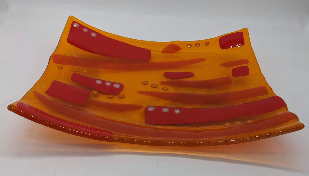 orange transparent glass with red stripes and white and yellow dots