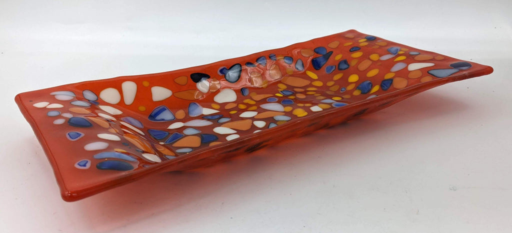 Orange glass tray with dots of blue, yellow, and white on top