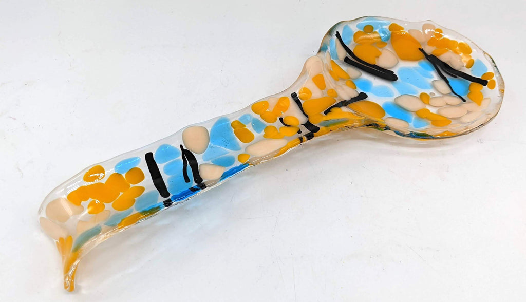 glass spoon rest with yellow, white, blue and black lines