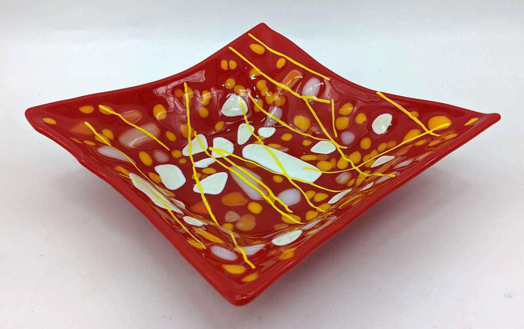 red glass bowl with dots of white and orange with yellow lines on top
