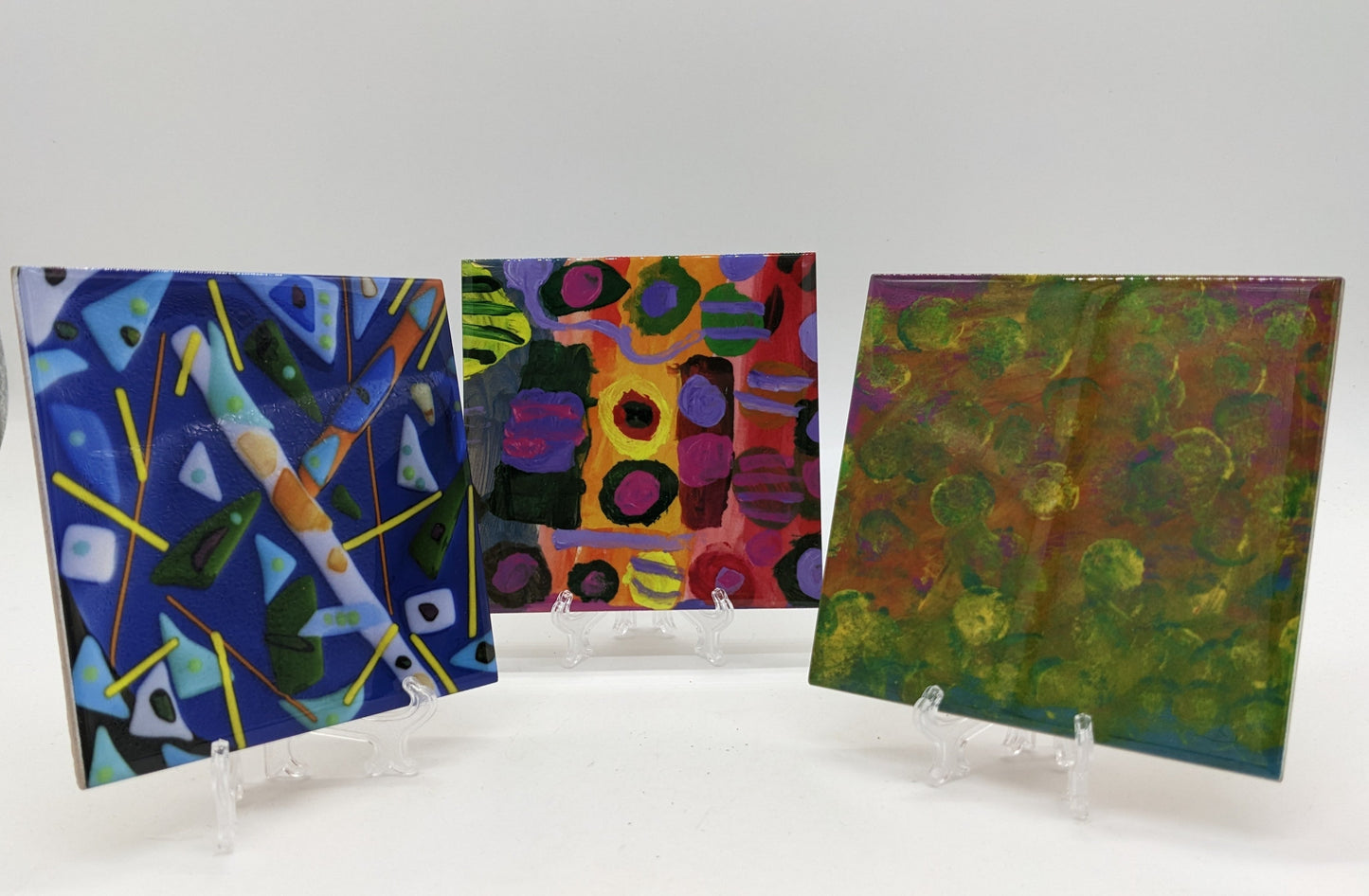 three ceramic coasters on clear easel
