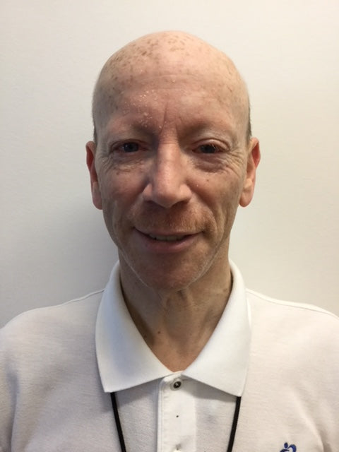 bald man smiling wearing a white collared shirt