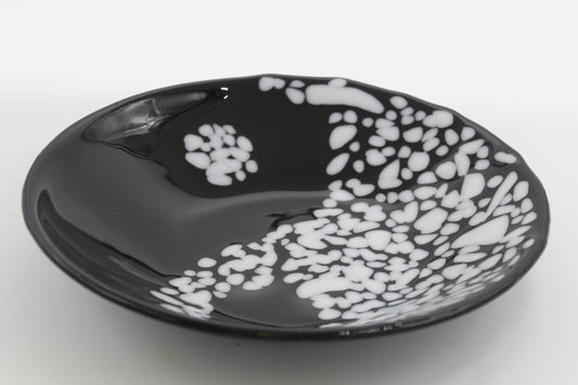 This is a black bowl resembling a yin yang figure. One side is made up of white dots and the other is black with a white dot