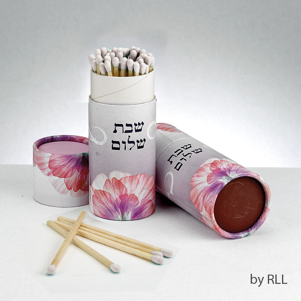 white cylinder with pink flower and Shabbat Shalom written in Hebrew. Matches are sticking out the top.