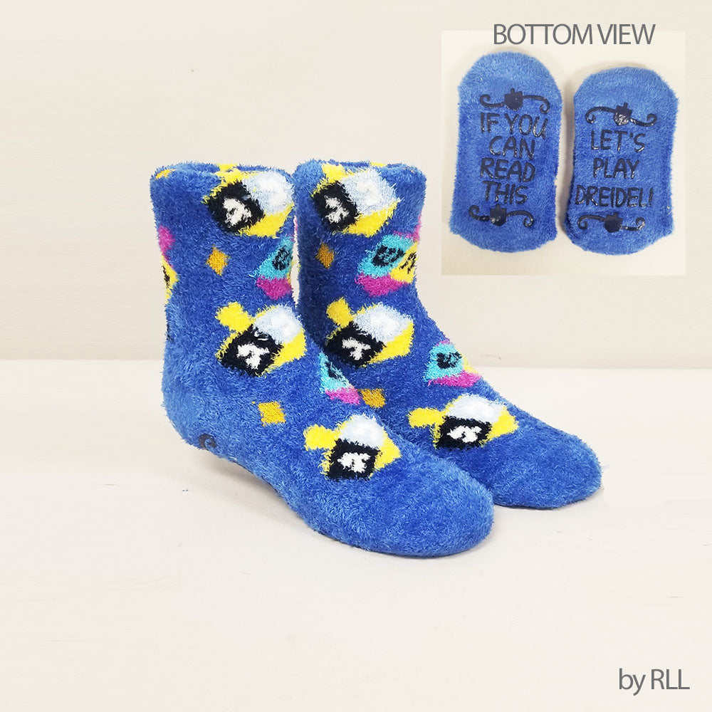 blue fuzzy socks with dreidel design. smaller box showing the bottom of slippers with words reading If you can read this let me play dreidel