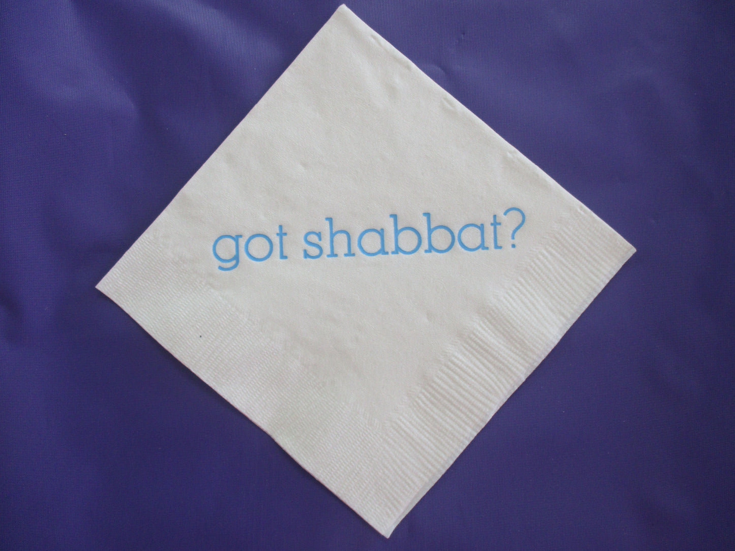White cocktail napkin with light blue got Shabbat? slogan
