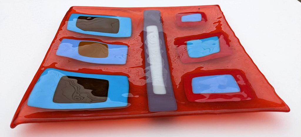red glass square shallow tray with layered rectangles on top of blues