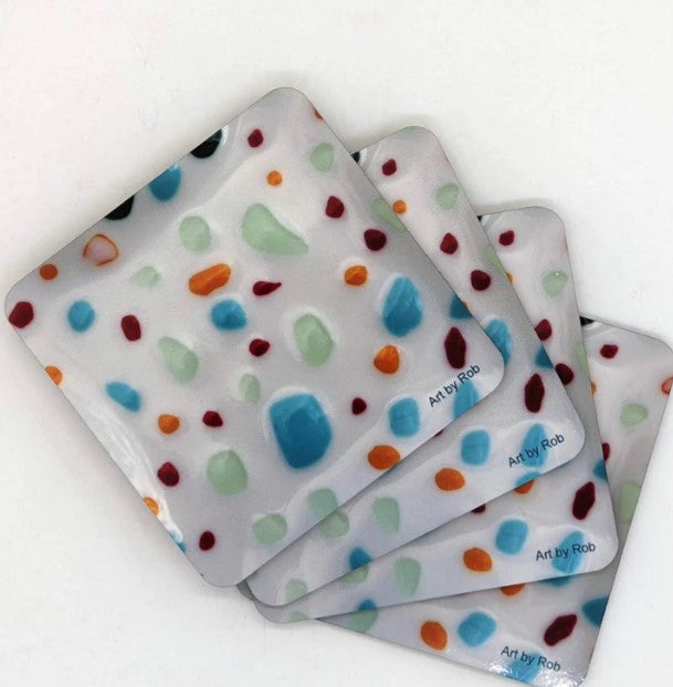 This is four coasters with the art on it - white background with blue, green, orange, red and black splotches of color.