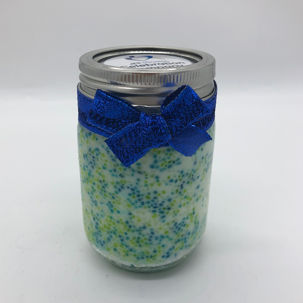 Canning jar with a white candle inside, blue and green round candy sprinkles decorating the sides.  Blue metallic bow on the outside.