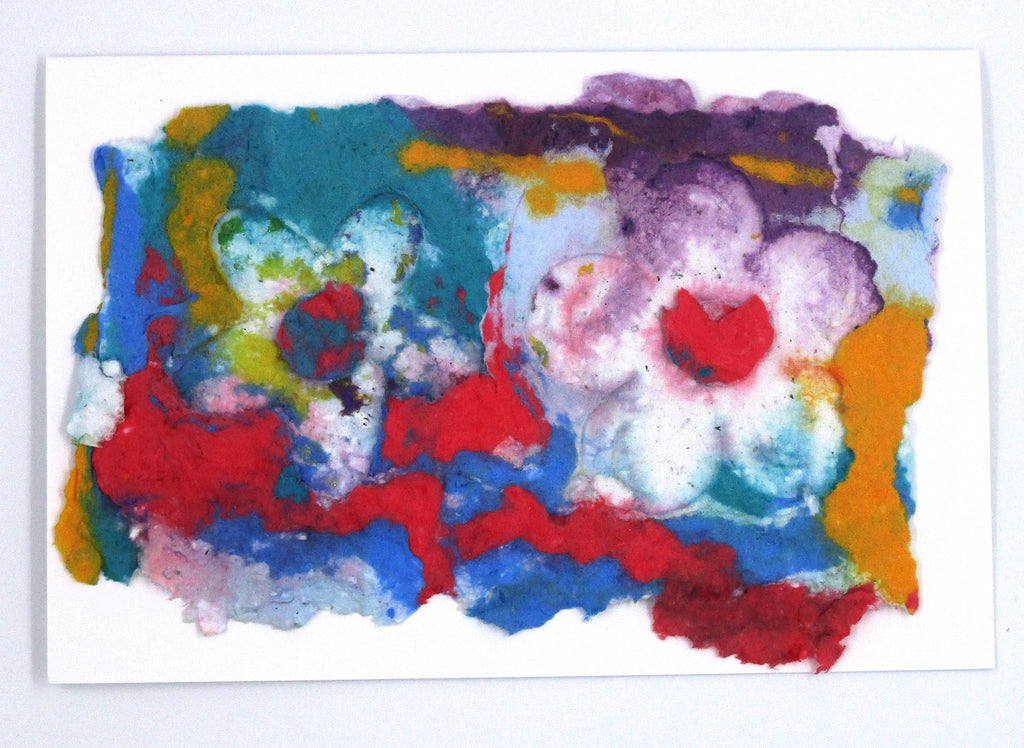 Handmade paper greeting card with red, yellow, blue, teal and purple colored background and two white flowers on top