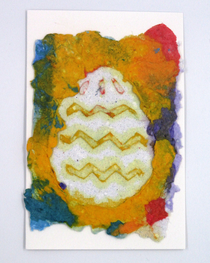 Handmade paper greeting card with yellow, red, blue and purple background with a white Easter egg over top