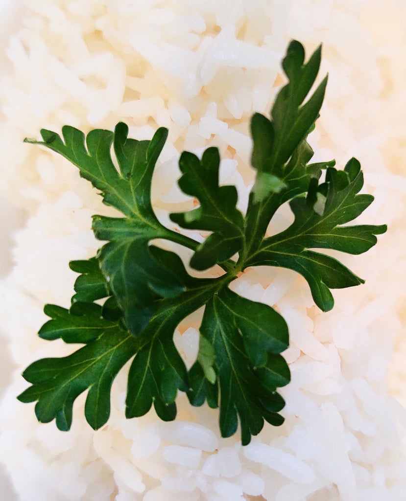 Photograph of a green leafy herb amongst white rice