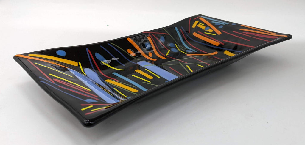 black glass rectangular tray with lines of various thickness and colors going mostly vertically across the piece