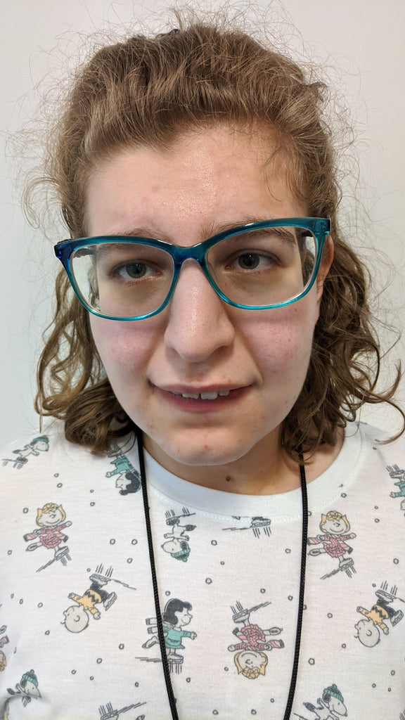 Smiling young woman with brown hair and teal colored glasses