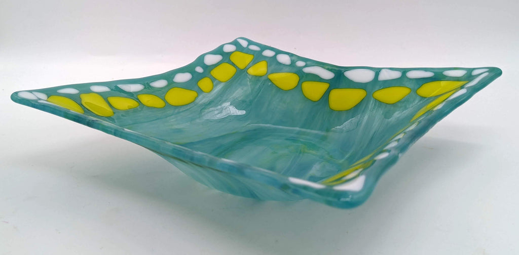 square glass bowl with shades of green and a border highlighted in white and yellow stones 