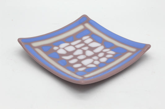 This is a glass sqaure piece of art that is purple It has blue and white lines outlining the edge of the piece, and blue and white splothces in the center